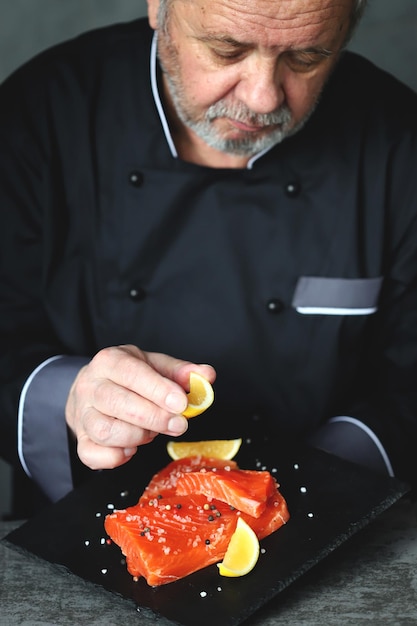 El chef sirve salmón en una pizarra negra Chef de sushi y pescado
