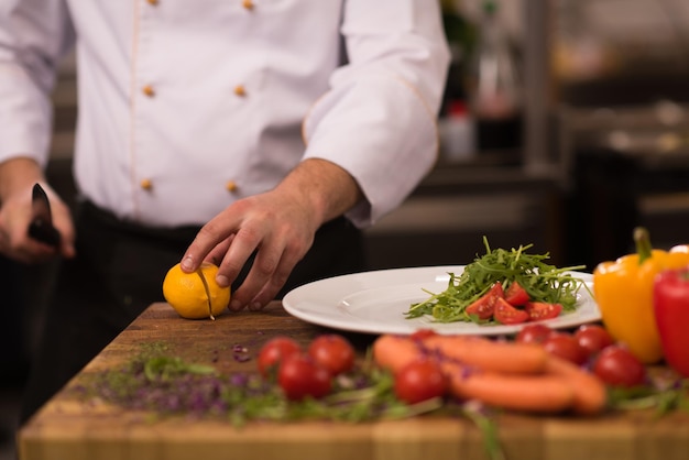 chef sirviendo ensalada de verduras en un plato en la cocina del restaurante