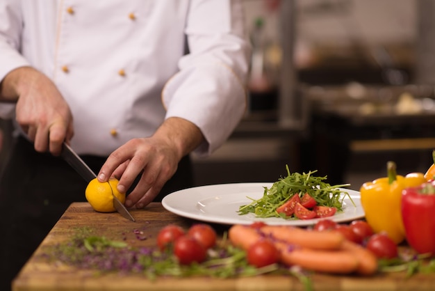 Chef sirviendo ensalada de verduras en un plato en la cocina del restaurante