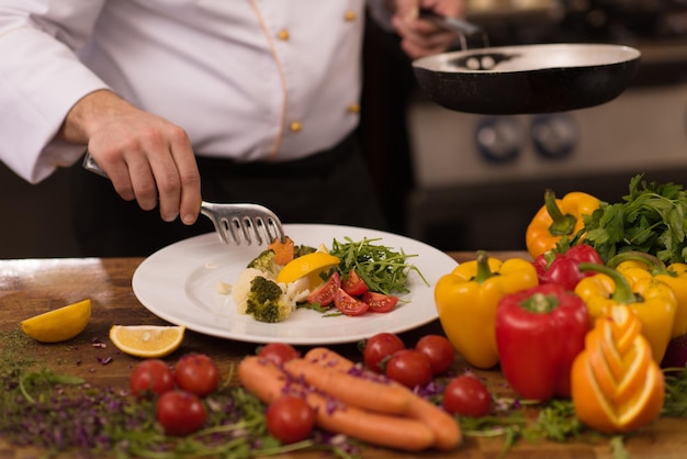 Chef sirviendo ensalada de verduras en un plato en la cocina del restaurante