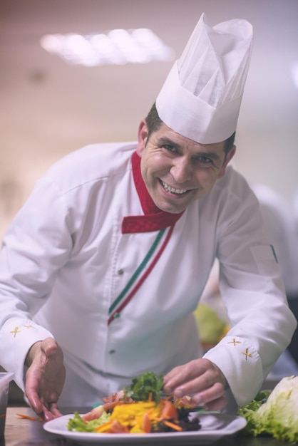 chef sirviendo ensalada de verduras en un plato en la cocina del restaurante