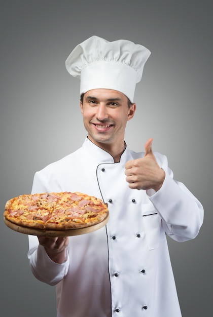 Chef sonriente con pizza fresca mostrando los pulgares hacia arriba