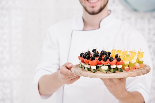 Chef sorridente em uniforme segurando lanches