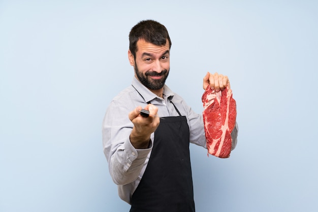 Chef sosteniendo una carne cruda apuntando hacia el frente