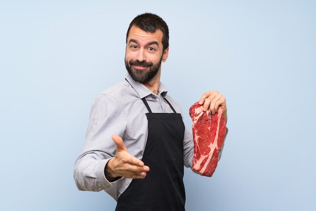 Chef sosteniendo una carne cruda estrechándole la mano para cerrar un buen trato