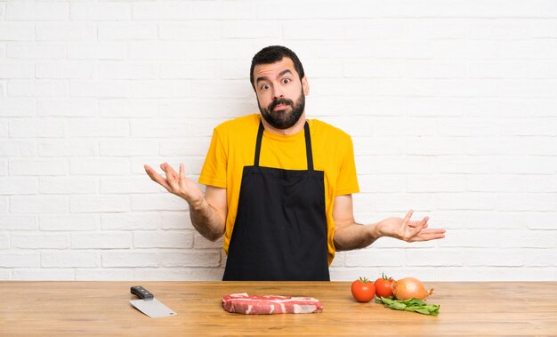 Chef sosteniendo en una cocina haciendo gestos de dudas.