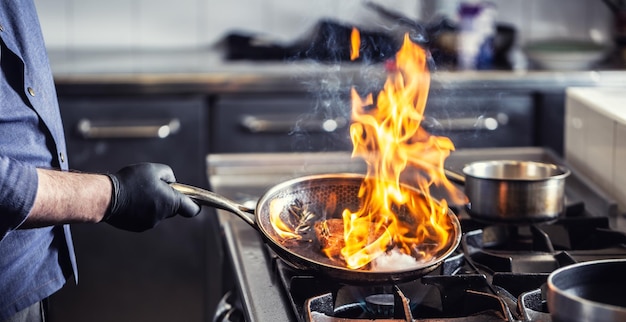 Chef sosteniendo pan realizando flambeado en un plato en él