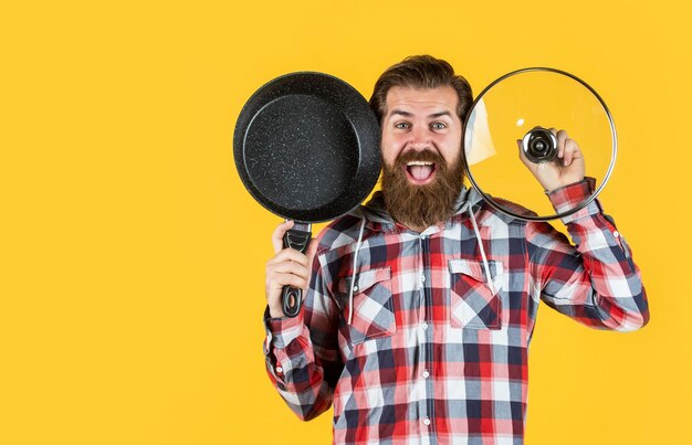 Chef de superficie antiadherente cocinando la cena chico maduro en camisa a cuadros con sartén hombre elegante va a cocinar comida hombre barbudo con bigote usa utensilios de cocina comiendo sano