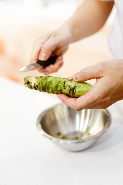 Chef de sushi grating Wasabi fresco, raíz de wasabi fresco se prepara para sushi nigiri