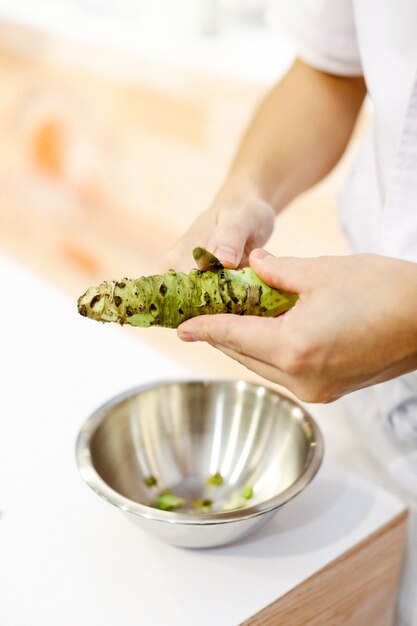 Chef de sushi grating Wasabi fresco, raíz de wasabi fresco se prepara para sushi nigiri