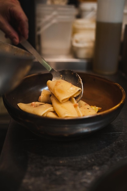 Foto el chef termina de servir la pasta rigatoni en un plato listo para ser servido a los comensales