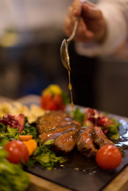 Chef terminando o prato de carne de bife com molho de prato final e quase pronto para servir à mesa