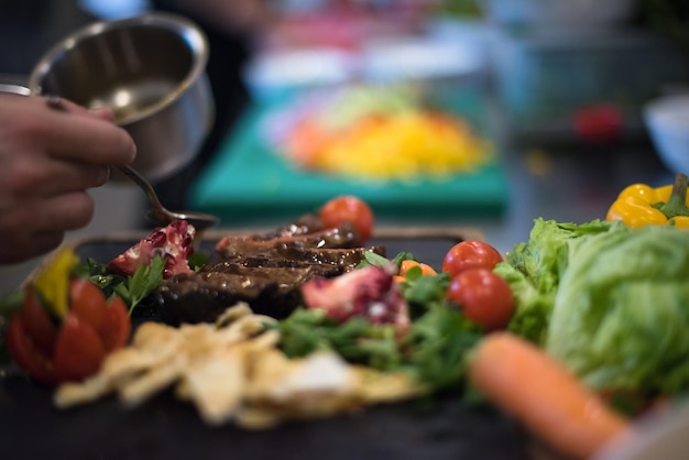 El chef terminó a mano el plato de carne de bistec con el aderezo para platos Finalmente y casi listo para servir en la mesa