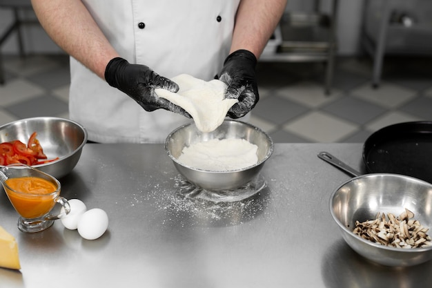 Foto chef está trabajando en la cocina con masa de pizza