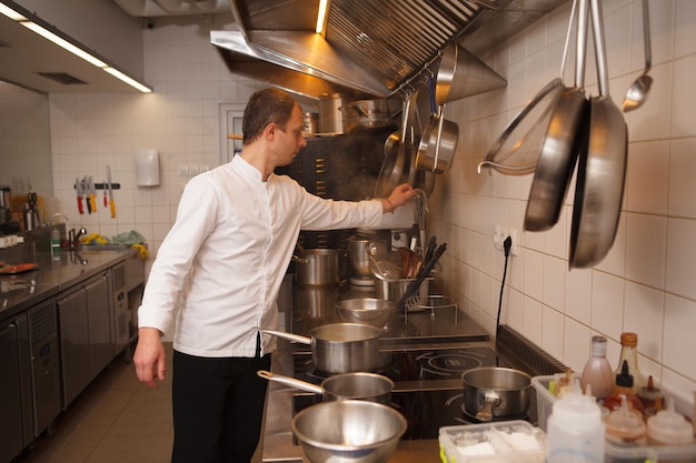 Chef trabalhando na cozinha do restaurante, usando utensílios de cozinha