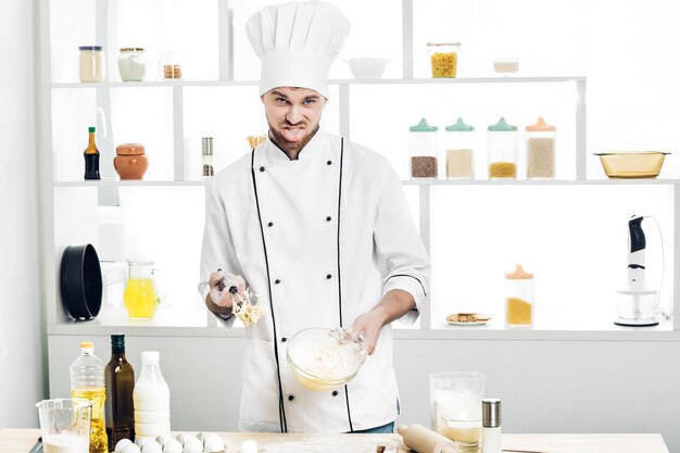 Chef en uniforme hace masa en la cocina. Mala masa