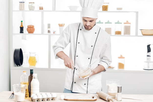 Chef en uniforme hace masa en la cocina