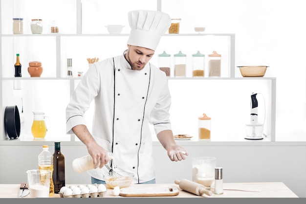 Chef en uniforme hace masa en la cocina