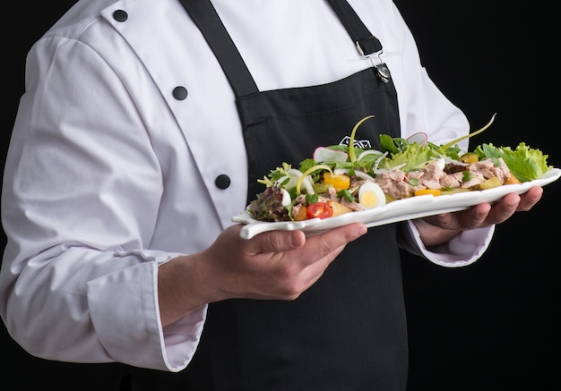 Chef en uniforme sirve un plato en un plato