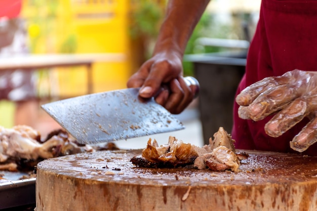 Foto el chef está usando un cuchillo para cortar el cochinillo asado