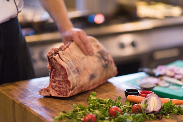 chef usando machado enquanto corta um grande pedaço de carne em uma placa de madeira na cozinha do restaurante