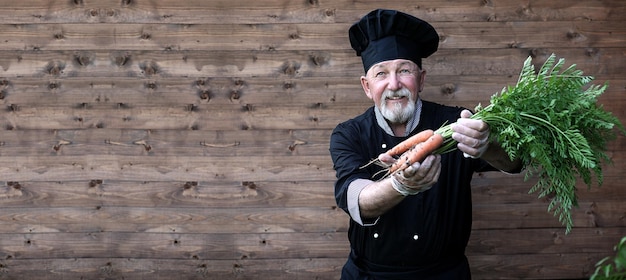 Chef velho de uniforme com legumes