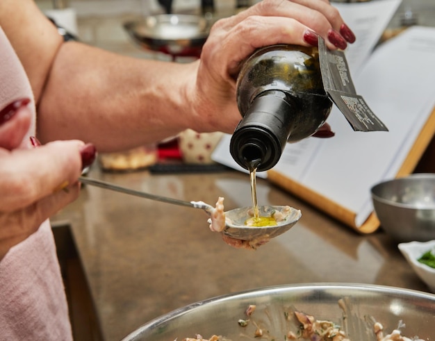 El chef vierte aceite de oliva de una botella en un plato de salmón