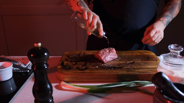 Foto el chef vierte aceite de oliva sobre la carne cruda que yace en una tabla de madera