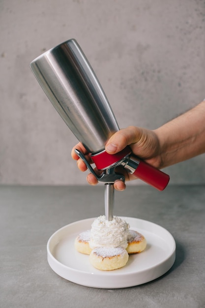 Foto el chef vierte espuma sobre tortitas de queso.