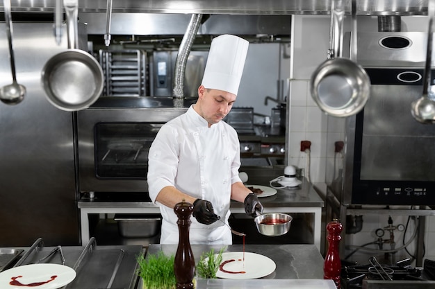 Chef vierte salsa de fresa roja en un plato