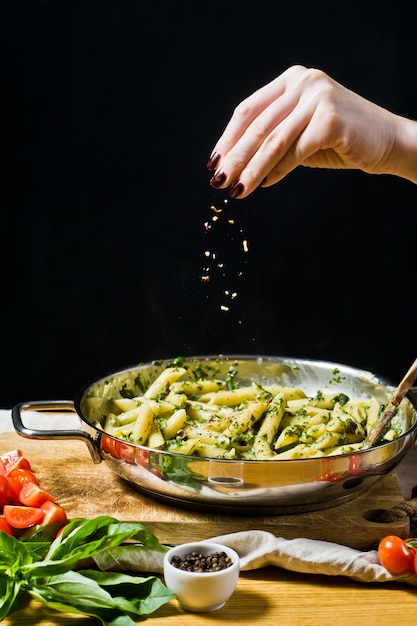 Chef vierte la salsa en la pasta Penne con espinacas.