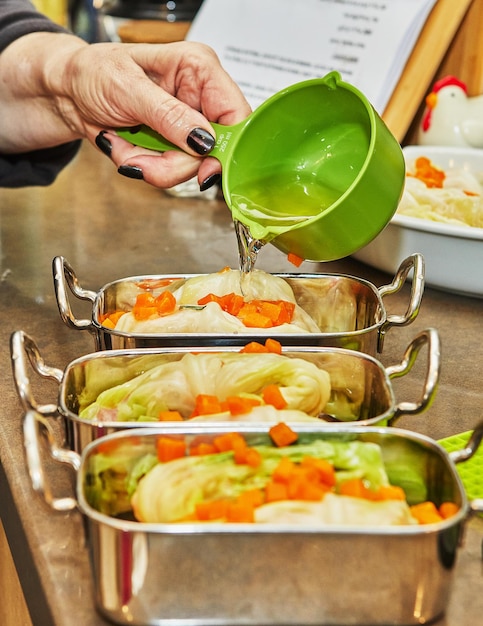 Chef vierte salsa en rollos de repollo con zanahorias de salmón en la cocina Receta francesa