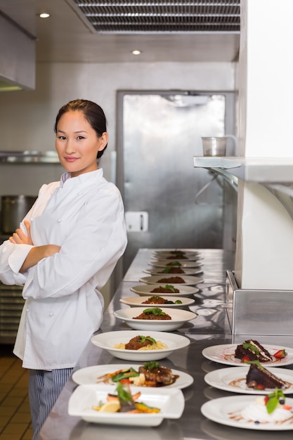 Foto chefe confiante, além de comida cozida em linha na cozinha