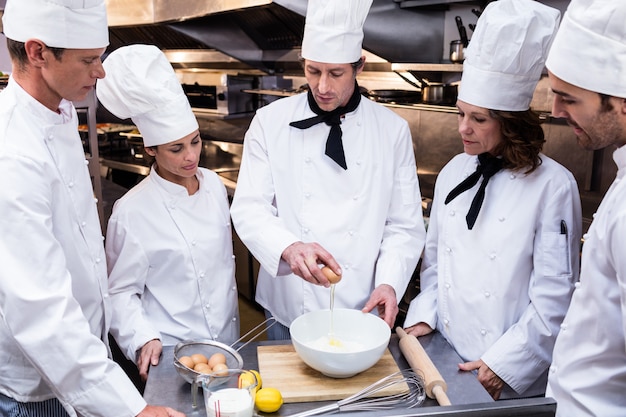 Chefe de cozinha ensinando sua equipe a preparar uma massa