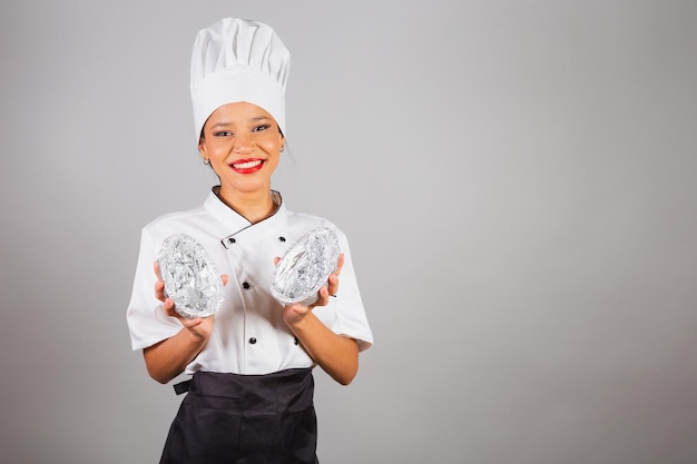 Chefe de cozinha nordestino segurando um ovo de Páscoa de chocolate em forma de ovo especialista no preparo de chocolates