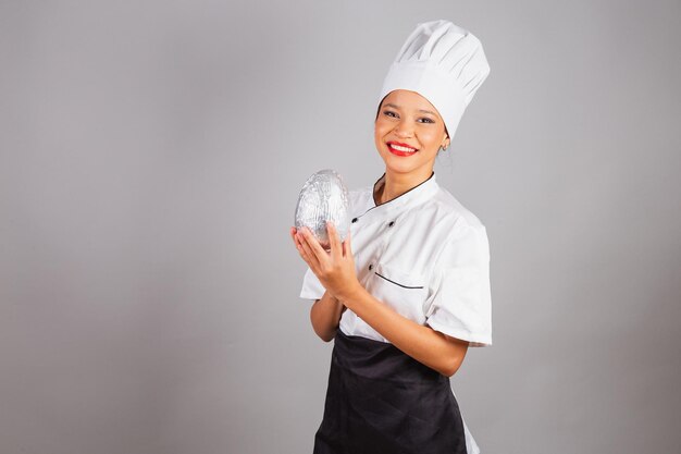 Foto chefe de cozinha nordestino segurando um ovo de páscoa de chocolate em forma de ovo especialista no preparo de chocolates