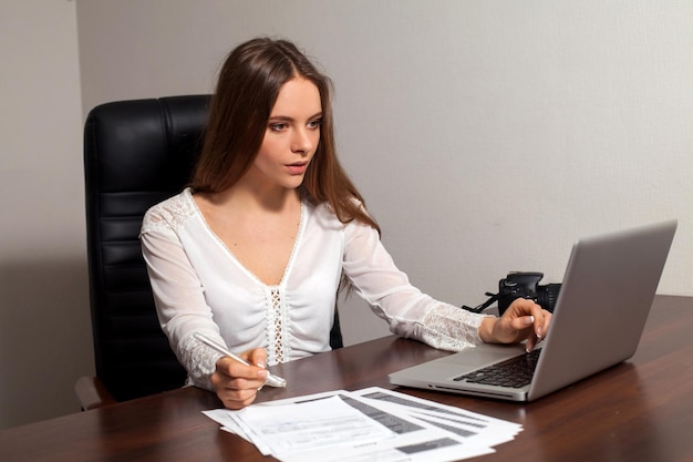 Chefe de mulher está sentado na cadeira e fazendo seu trabalho no escritório