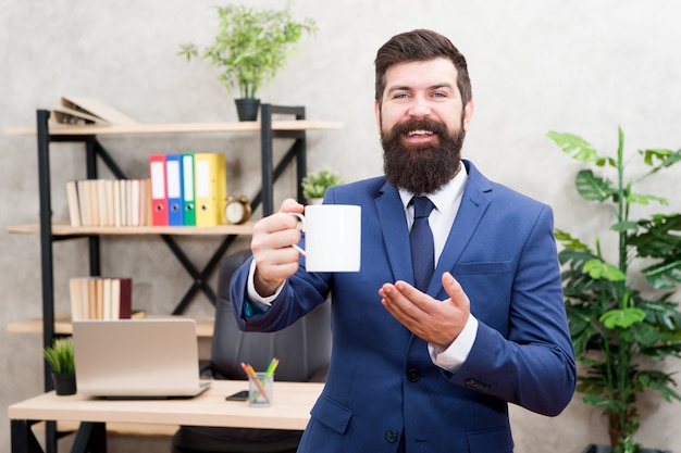 Chefe desfrutando de uma bebida energética. Viciado em cafeína. Comece o dia com um café. Homem barbudo empresário segurar fundo de escritório de carrinho de xícara de café. Pessoas bem-sucedidas bebem café. Uma pausa relaxante para beber café.