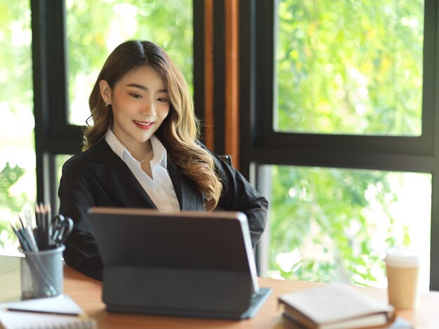 Chefe do gerente de produto procurando trabalho no tablet em seu escritório, empresária bem-sucedida asiática