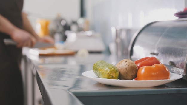 Chefe na cozinha do restaurante corta legumes para salada - conceito de culinária, tiro desfocado