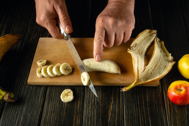 Chefes a cortar bananas numa tábua de madeira.