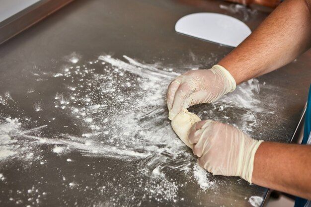 Chefhände bereiten Apfelkuchen in der Restaurantküche zu. Der Prozess der Herstellung von süßen Brötchen. Roher Teig zum Backen im Ofen.