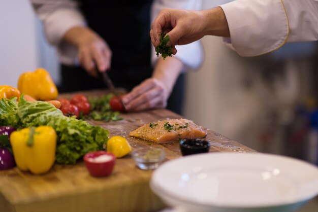 Chefkoch bereitet mariniertes Lachsfischfilet zum Braten in einer Restaurantküche vor