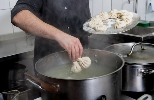 Chefkoch coocking georgian Khinkali oder japanischer Wonton. Traditionelle Mahlzeit aus Teig und Fleisch. Nationale Küche, Kochprozess. Restaurant Küche.