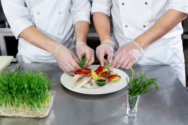 Chefkoch dekoriert Microgreens Fisch mit Gemüse