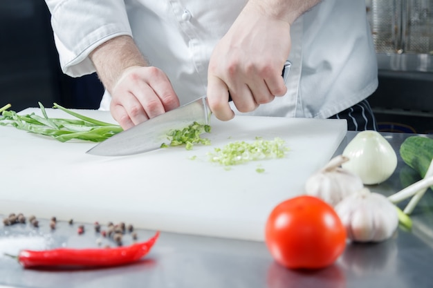 Chefkoch, der grüne Zwiebel für die Zubereitung des gesunden Gemüsesalats kocht