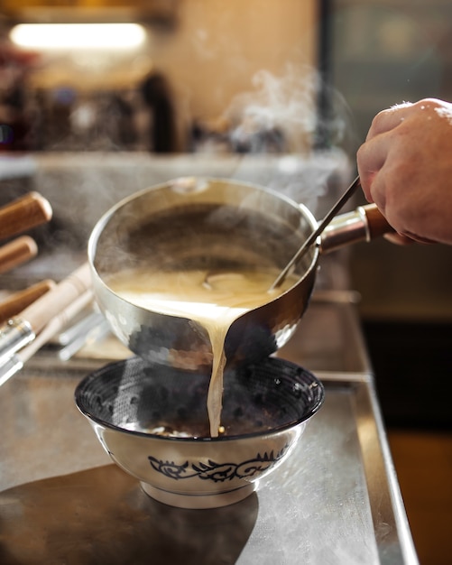 Chefkoch, der japanische Ramen-Nudelsuppe mit Brühe kocht