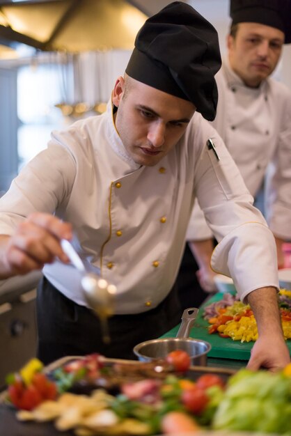 Chefkoch fertigt Steakfleischplatte mit Final Dish Dressing und ist fast servierfertig am Tisch