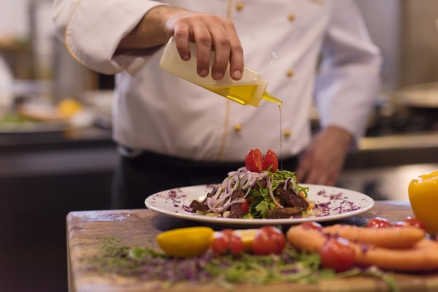 Chefkoch fertigt Steakfleischplatte mit Final Dish Dressing und ist fast servierfertig am Tisch