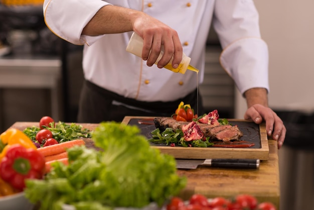 Chefkoch fertigt Steakfleischplatte mit Final Dish Dressing und ist fast servierfertig am Tisch